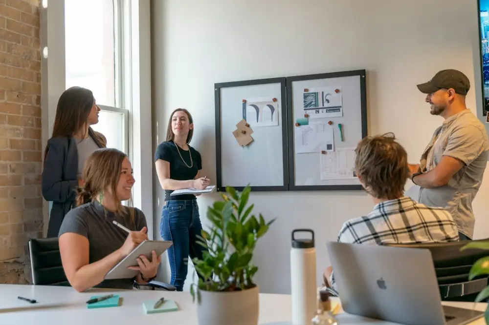 A group of people in a sunlit office during a collaborative workspace meeting, illustrating accountable leadership
